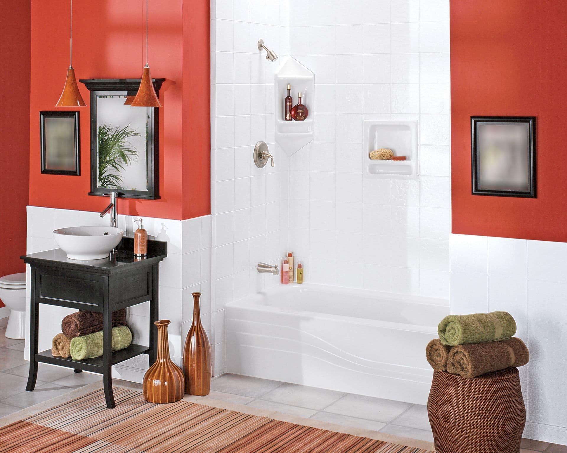 Modern bathroom with bold red walls and white tiles. Features a shower-tub, vessel sink on a dark vanity, and rolled towels on a wicker basket. Warm, stylish ambiance.